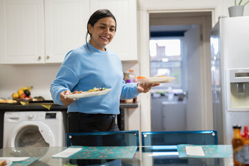 Woman carrying plates with lunch in kitchen - obrazy, fototapety, plakaty
