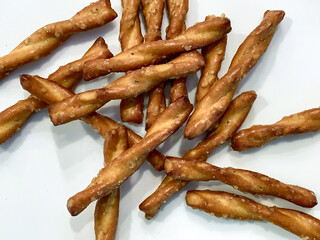 Twisted pretzel sticks stacked on a white background