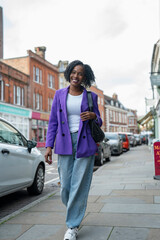 Fototapeta premium Smiling woman in purple jacket walking in city