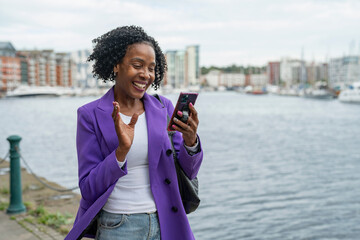 Smiling woman using smart phone by river