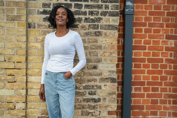 Portrait of smiling woman standing by brick wall © Cultura Creative