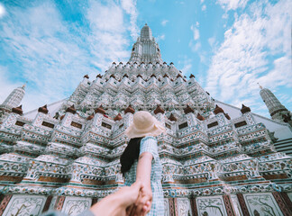 Couple holding hands with woman behind is a Thai temple