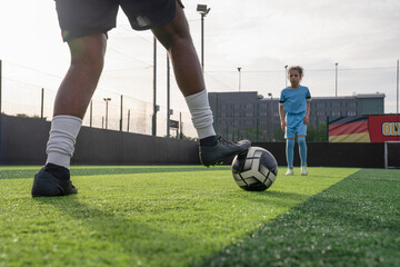 Man and girl (6-7) playing soccer on soccer field