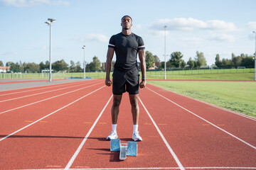 Fototapeta premium Athlete standing in front of starting line at running track