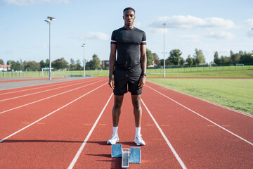 Athlete standing in front of starting line at running track