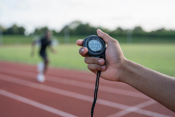 Male hand holding stopwatch during athletes sprint