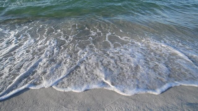 Emerald green ocean waves rolling up on a sand beach