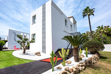 Fototapeta premium an image of the entrance to a luxury Mediterranean villa filled with cactus plants and a swimming pool 