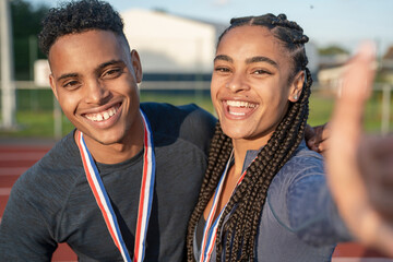 Portrait of male and female athlete celebrating with medals
