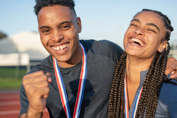 Portrait of male and female athlete celebrating with medals