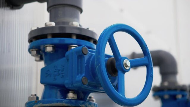 Metal valve on pipe with flange connection under high pressure at sewage treatment plant closeup. Round lever on pipeline system at factory