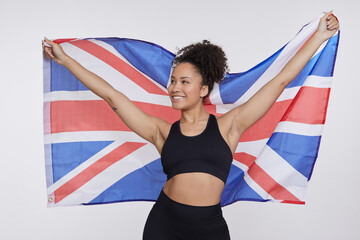 Studio portrait of smiling athletic woman holding British flag