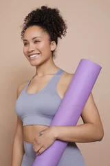 Tuinposter Studio portrait of smiling athletic woman with yoga mat © Cultura Creative