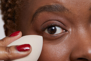 Close-up of woman applying make up foundation with sponge - obrazy, fototapety, plakaty