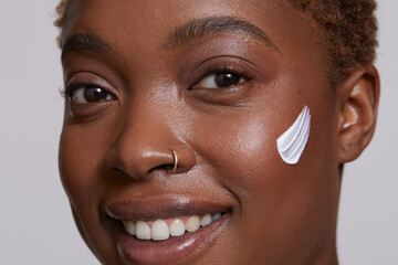Close-up of smiling woman with face cream on cheek