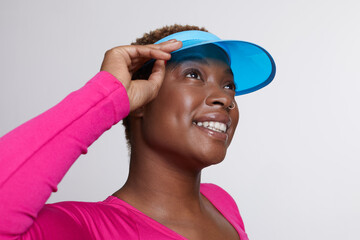 Studio portrait of smiling woman wearing blue sun visor and pink shirt