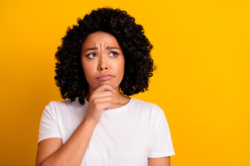 Portrait of puzzled minded girl with curly hairdo wear white t-shirt look at proposition empty...