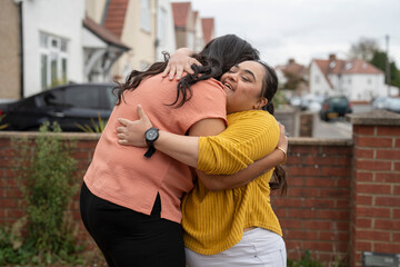 Down syndrome daughter embracing mother in front of house
