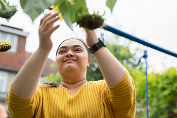 Young woman with down syndrome touching flower in garden