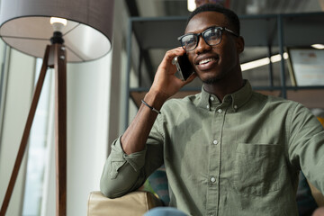 Young man with smartphone sitting in office lounge