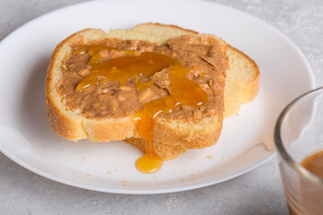 Sandwich with honey and peanut butter spreading on piece of white bread toast, close up. Typical snack food, food lifestyle, domestic life, american breakfast