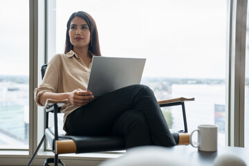 Businesswoman with laptop sitting in office lobby