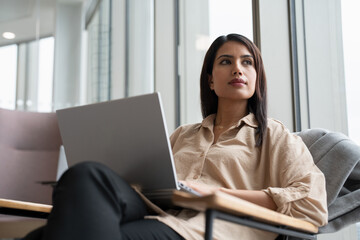 Businesswoman with laptop sitting in office lobby