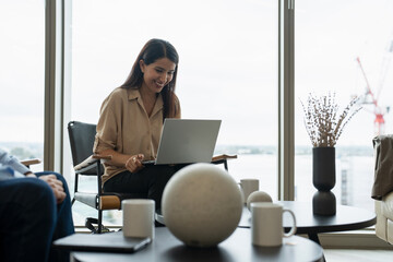 Businesswoman with laptop sitting in office lobby