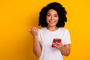 Photo of charming lovely woman with chevelure holding smartphone indicating at discount empty space...