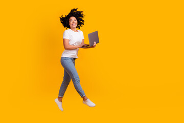 Full length photo of excited funky lady dressed white t-shirt jumping high walking chatting gadget empty space isolated yellow color background