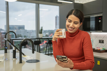 Woman using smart phone in office kitchen © Cultura Creative