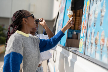 Young female friends buying ice cream in ice cream truck