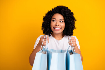 Portrait of optimistic girl wear casual t-shirt hold shopping bags look at discount empty space...