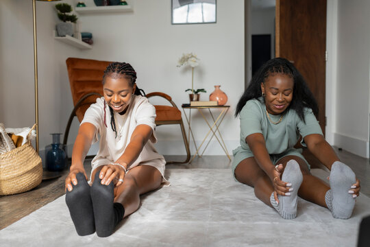 Lesbian Couple Stretching On Floor At Home