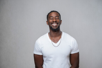 Portrait of smiling man with closed eyes, wearing white t-shirt and necklace - obrazy, fototapety, plakaty