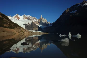 Papier Peint photo Cerro Torre Snowy peaks reflected in the mountain lake, Cerro Torre, Adela Ridge and calm waters of Laguna Torre with small icebergs under the blue sky, Southern Patagonian Ice Field in South America, Argentina