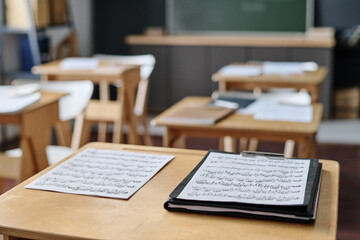 Selective focus no people shot of sheet music papers on wooden desk in modern classroom at school