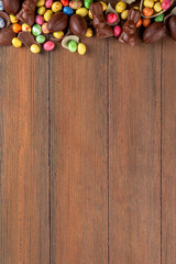 Easter background greeting card with holiday traditional confectionery, Easter egg hunt fun concept. Chocolate bunny, chocolate and candy Easter eggs on wooden background