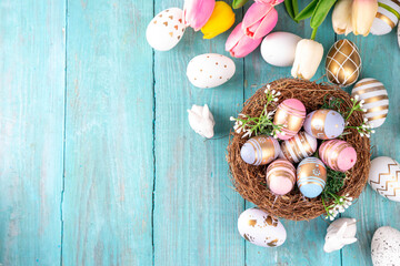 Obraz na płótnie Canvas Easter nests and eggs background with spring flowers, Happy Easter holiday greeting card flat lay on wooden background, top view copy space