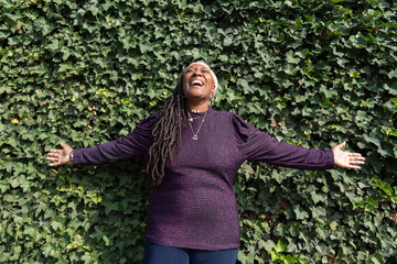 Portrait of beautiful woman with dreadlocks in front of ivy wall