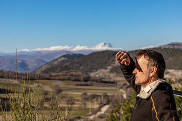 Castelvecchio Subequo, Italy A male hiker looks at a view of the town and  the Monte Sirente...