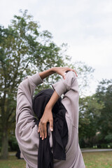 Rear view of woman in hijab stretching in park
