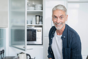Naklejka na ściany i meble Portrait of smiling mature man in kitchen