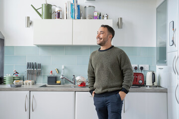 Smiling mature man standing in kitchen at home - obrazy, fototapety, plakaty