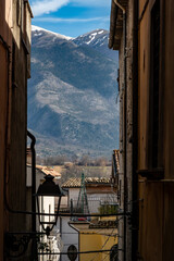 Pratola, Italy A view of the Montagne del Morrone mountains through a narrrow street and a street lamp.