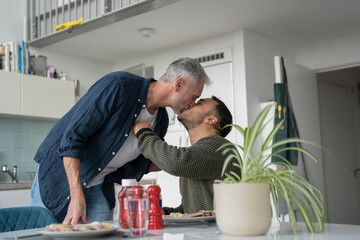 Male couple kissing and eating breakfast at home - obrazy, fototapety, plakaty