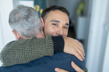 Male couple hugging at home