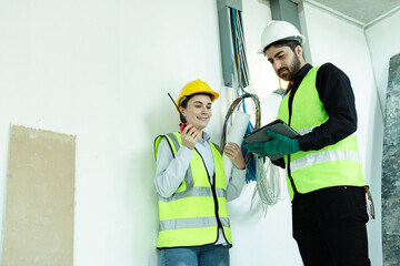 team electrical engineers or technicians is professionally inspecting the wiring and systems in the building. Check electrical equipment to meet safety standards. Use a tablet to check buildings.