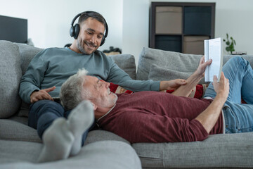 Smiling male couple relaxing on sofa at home