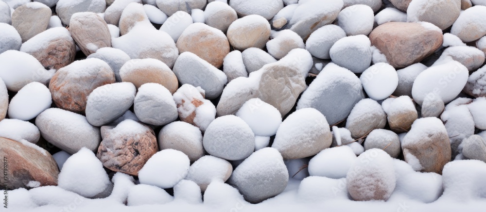 Poster a pile of rocks covered in a layer of snow, creating a stark contrast between the grey stones and th